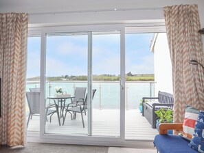 Ein Balkon mit Tisch und Stühlen, Blick aufs Wasser und einer Brüstung.