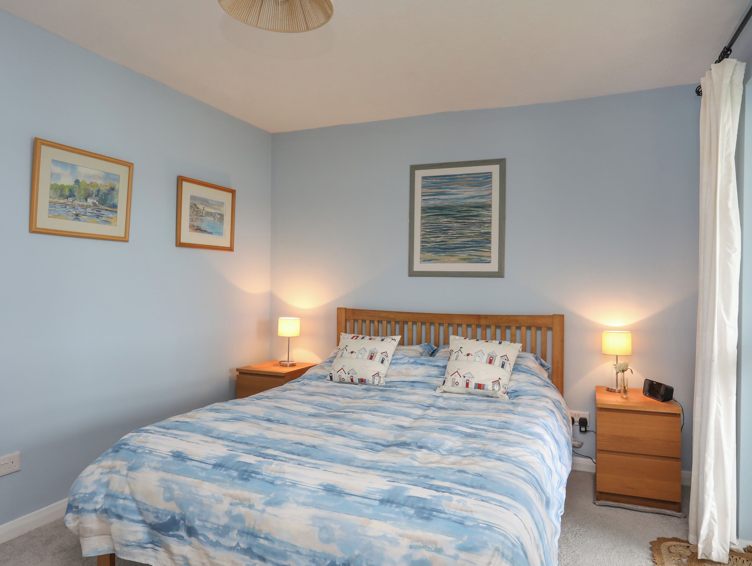 A bedroom with a bed, two bedside tables, and wall art.
