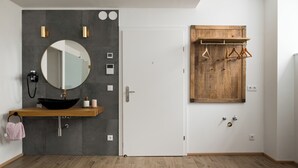A modern bathroom with a round mirror, black sink, and wooden vanity. - Vienne Prime Apartments (Vienna)