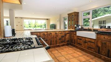 A spacious kitchen with wooden cabinets, a large island, and a view of greenery outside.