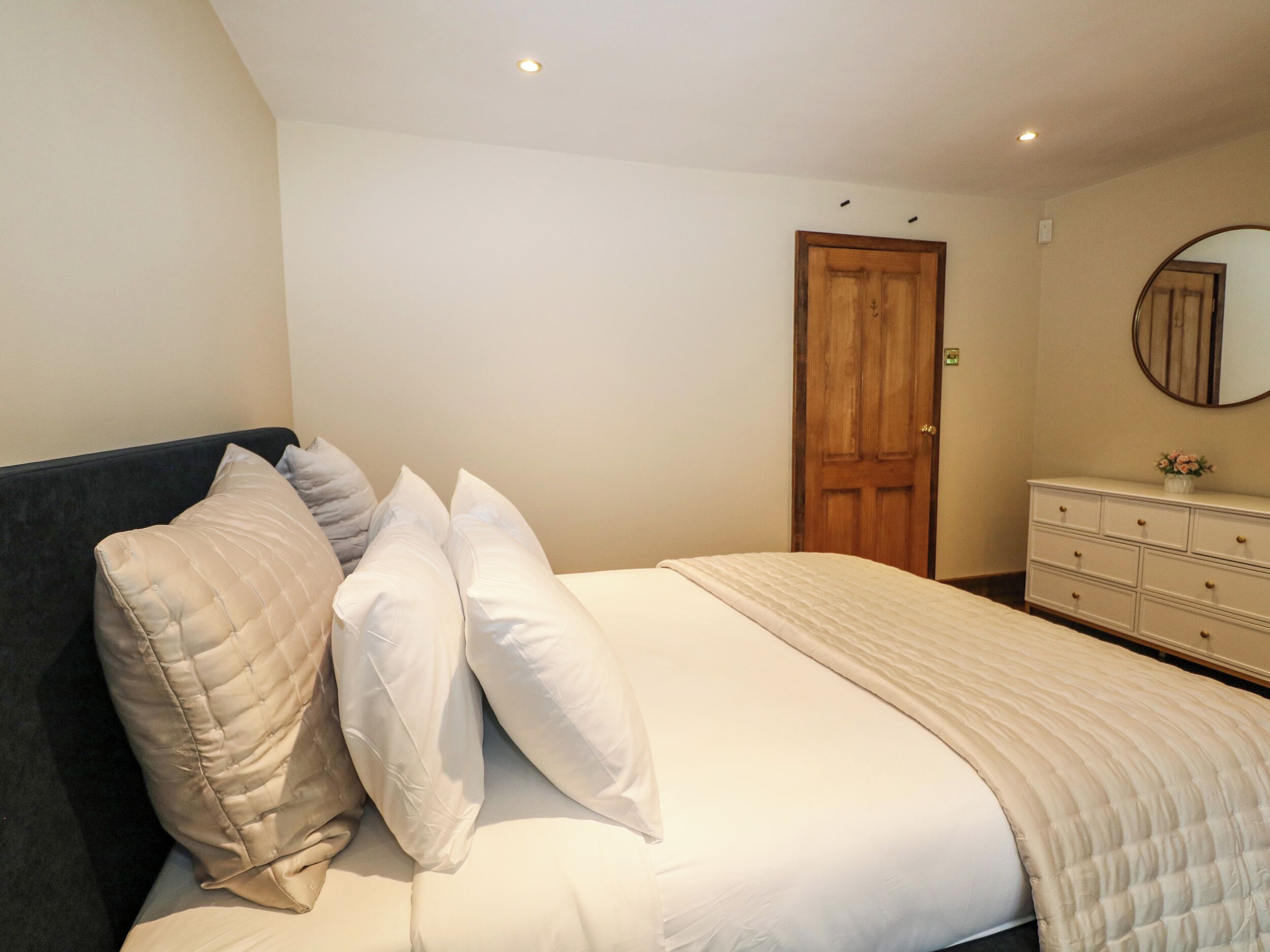 A bedroom with a bed, a dresser, a mirror, and a door.