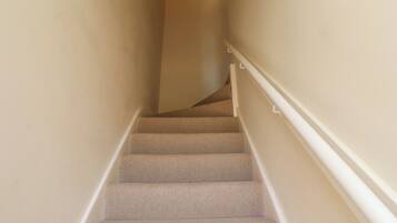 Una escalera empapelada con barandillas blancas, que conduce a un piso superior.