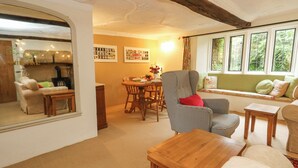 A cozy living room with a fireplace, a dining area, and a window seat with cushions. - The Elbow (Dorchester)