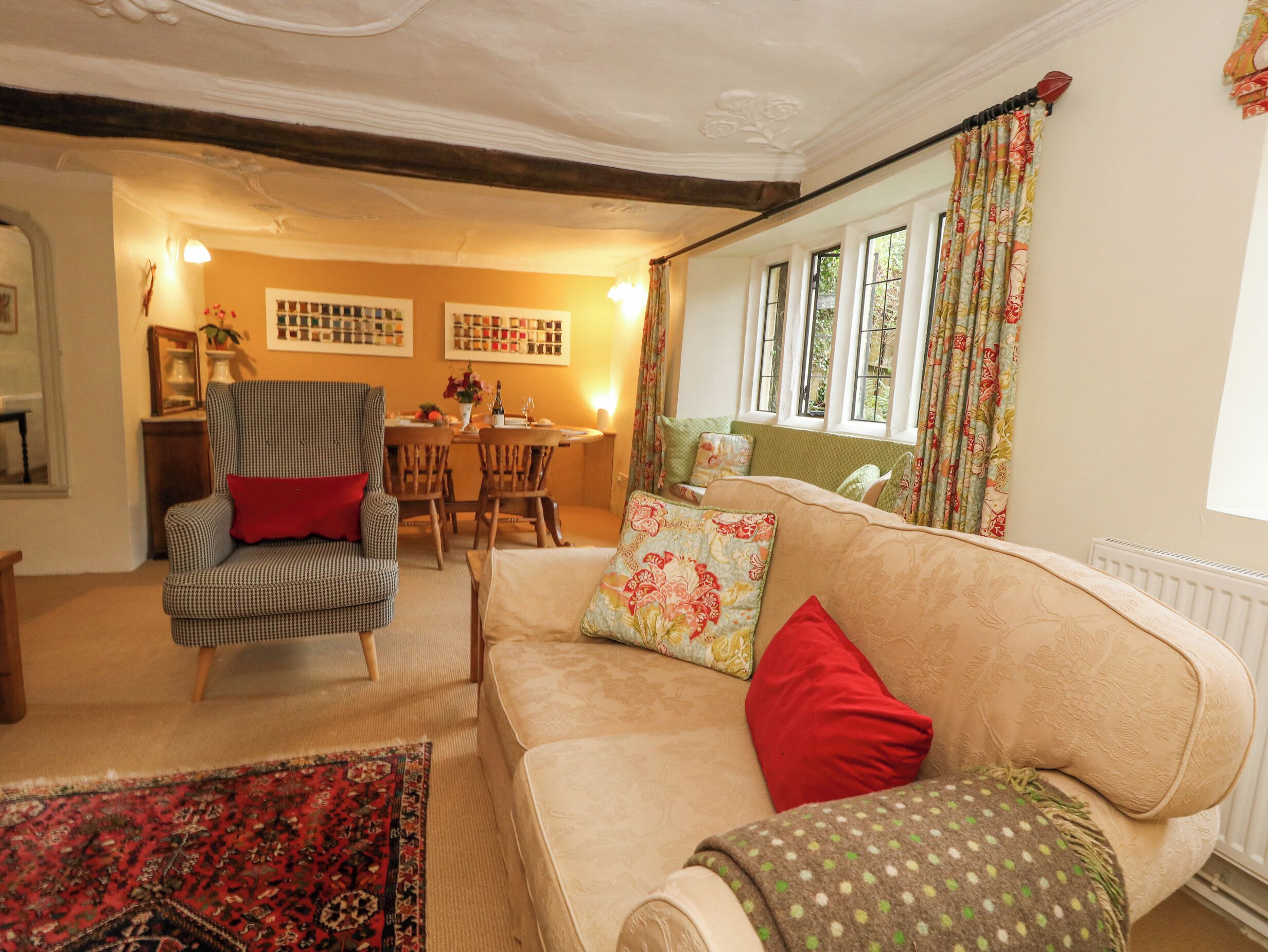 A cozy living room with a sofa, armchair, and a dining table with chairs.