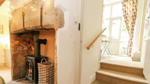 A cozy room with a stone fireplace, a wicker basket, and a staircase leading to a balcony. - The Elbow (Dorchester)