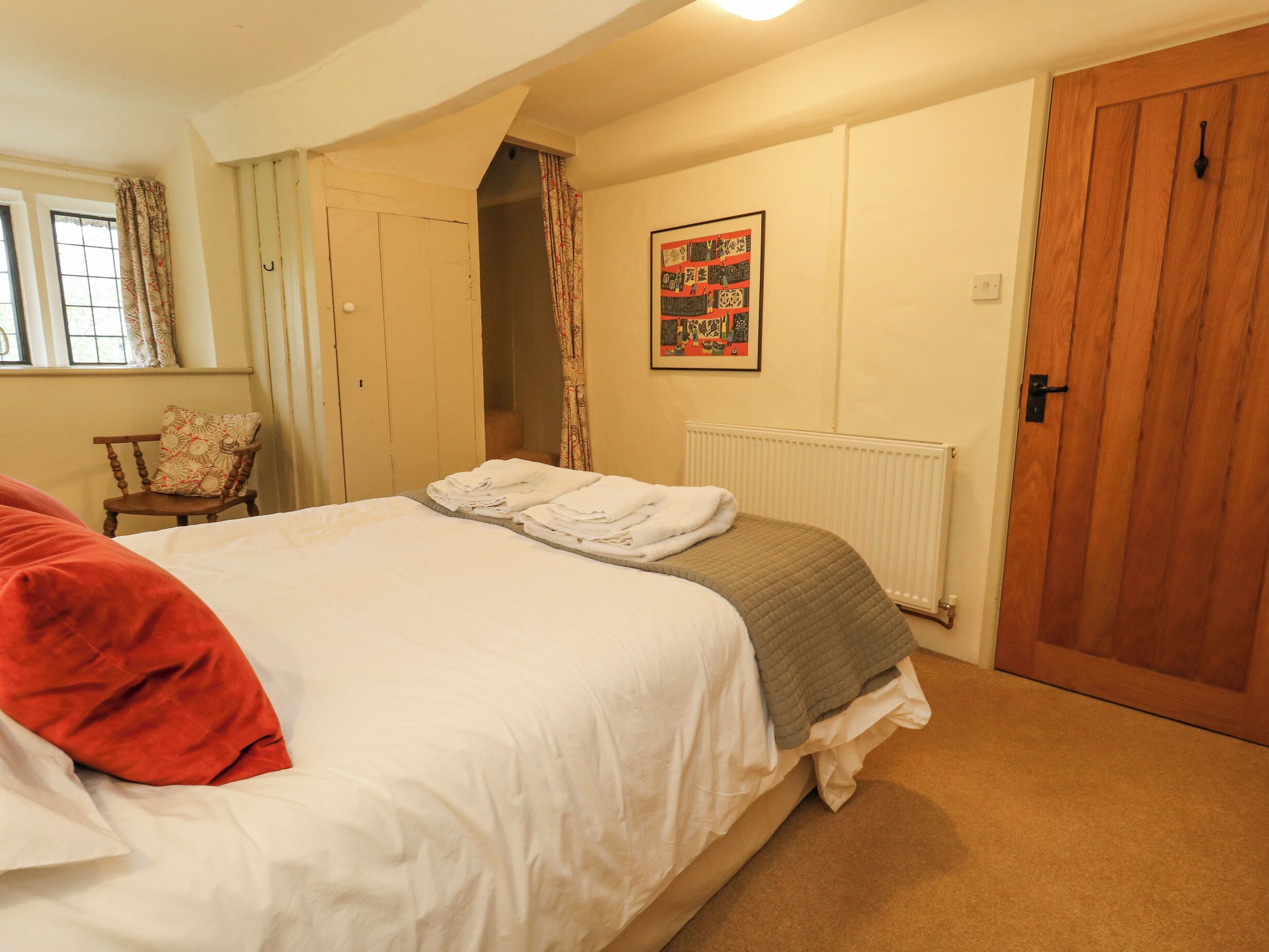 A bedroom with a bed, a chair, a radiator, and a wooden door.