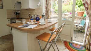 A kitchen with a wooden countertop, a sink, and a window overlooking a garden. - The Elbow (Dorchester)