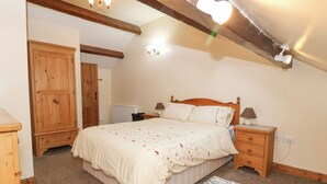 Quarto com cama de madeira, mesas de cabeceira, radiador e guarda-roupa de madeira.