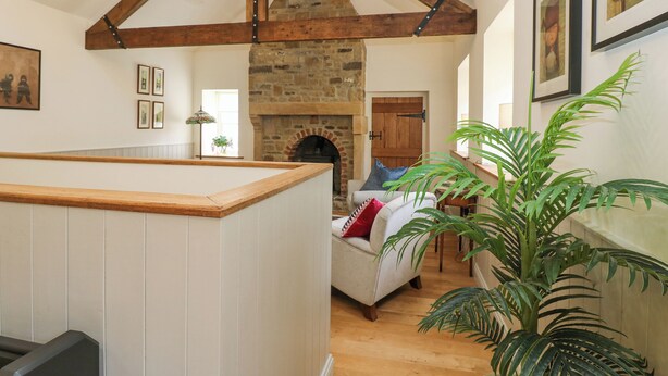 A cozy interior with a stone fireplace, wooden beams, and a seating area with a sofa and armchairs. - Jack's Cottage (Bishop Auckland)