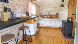 A compact cabin with a kitchenette, a bed, and a wood stove. - Llety Llanfair (Caernarfon)