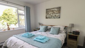 Een slaapkamer met een bed, twee nachtkastjes, een raam met gordijnen en een decoratie aan de muur.