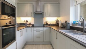 Een moderne keuken met witte kastjes, roestvrijstalen apparatuur en een houten vloer.