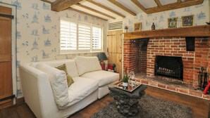 Ein gemütliches Wohnzimmer mit einem weißen Sofa, einem Kamin und Wandtapete mit Muster.