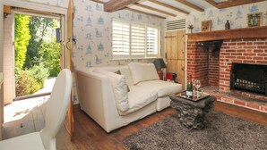 Ein gemütliches Wohnzimmer mit einem weißen Sofa, einem Kamin und einer Holzbalkendecke.