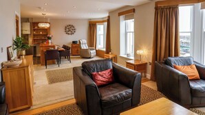 A spacious living area with a dining table, two leather sofas, and a kitchen in the background. - 43A Quay Street (Scarborough)