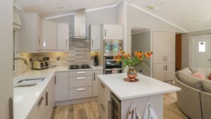 A modern kitchen with white cabinetry, a central island, and a skylight. - Waterside Lodge (Windermere)