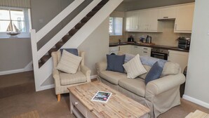 A modern living room with a staircase, a beige sofa set, and a wooden coffee table. - Aln Cottage (Alnwick)