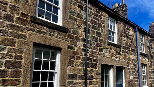 A stone building with multiple windows and a door, likely a residential property. - Aln Cottage (Alnwick)
