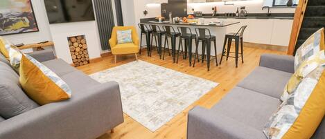 A modern living room with grey sofas, a yellow armchair, and a wooden floor.