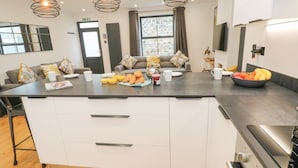 Una cucina moderna con un'ampia isola, elettrodomestici in acciaio inossidabile e luci a sospensione.