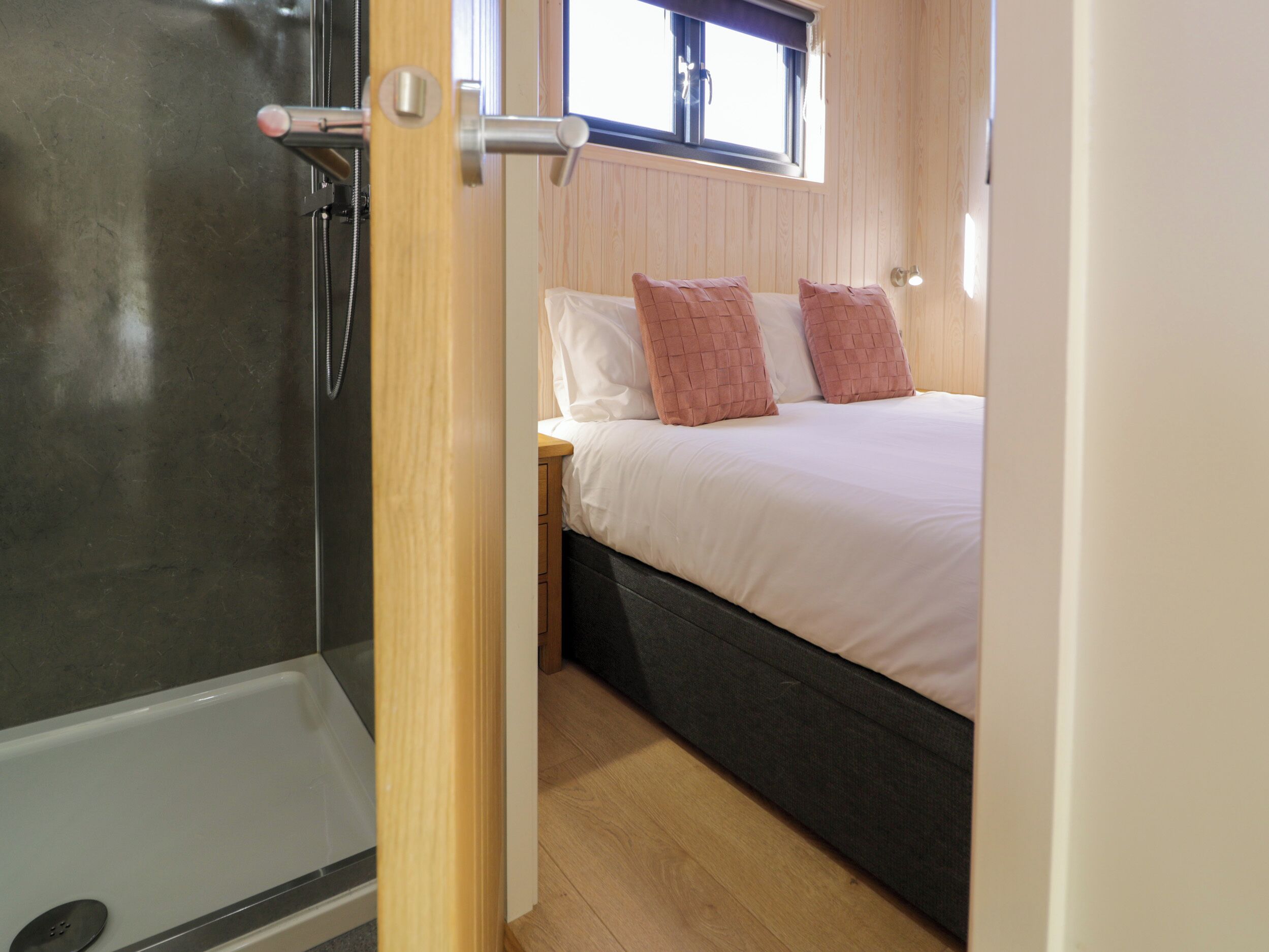 A bedroom with a bed, a window, and a shower area.