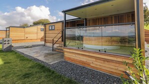 A modern wooden building with a glass enclosure, a stone pathway, and a grassy area. - Betsi (Ruthin)