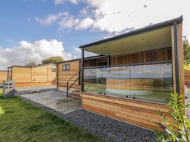 Un edificio moderno de madera con cerramiento de vidrio, un camino de piedra y una zona ajardinada.
