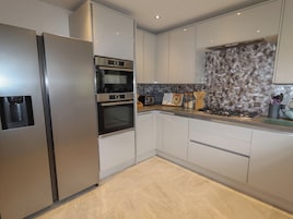 A modern kitchen with stainless steel appliances, a built-in oven, and a unique hexagonal backsplash.