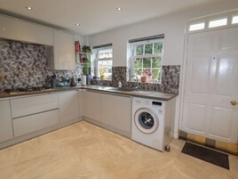 A modern kitchen with a built-in washing machine, a sink, and a window with a view of greenery.