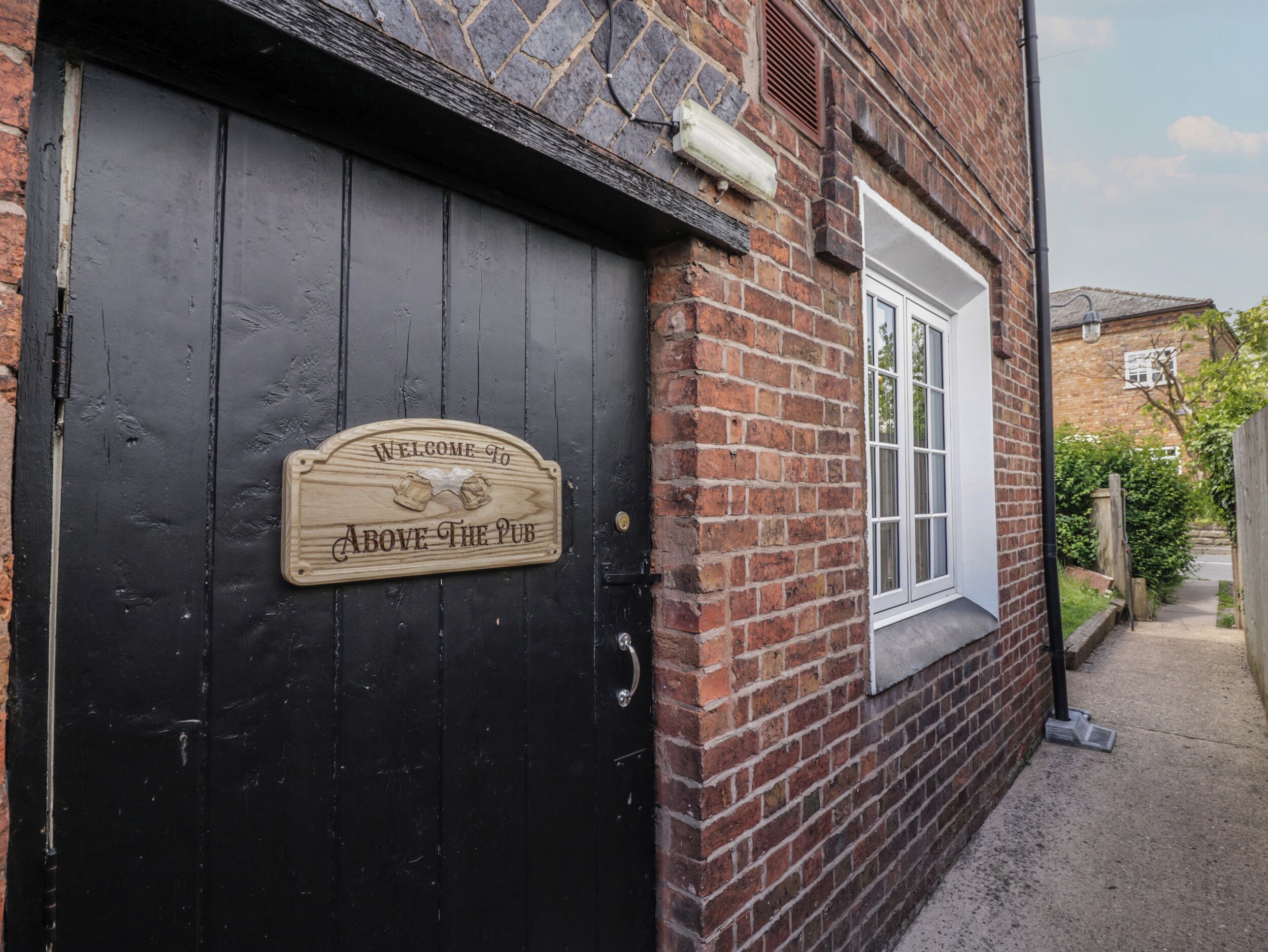 A black wooden door with a welcome sign for Above the Pub.