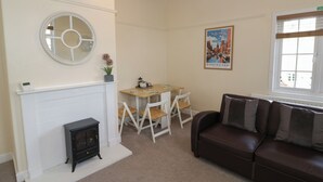 A living room with a fireplace, a dining table with chairs, a sofa, and a wall-mounted mirror. - Above The Pub (Birmingham)