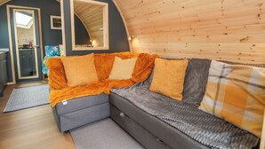 Una habitación acogedora con sofá, espejo y vistas a una cocina.