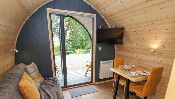 Una habitación acogedora con una cama, una mesa de comedor con sillas, un televisor en la pared y un ventanal grande.