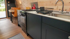Una cocina compacta con estufa, lavamanos y un comedor con una silla y mesa.