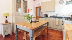 A kitchen with wooden cabinets, a dining table with a bench, and a vase with flowers.
