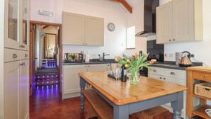 A modern kitchen with wooden beams, a dining table with tulips, and a view into another room.