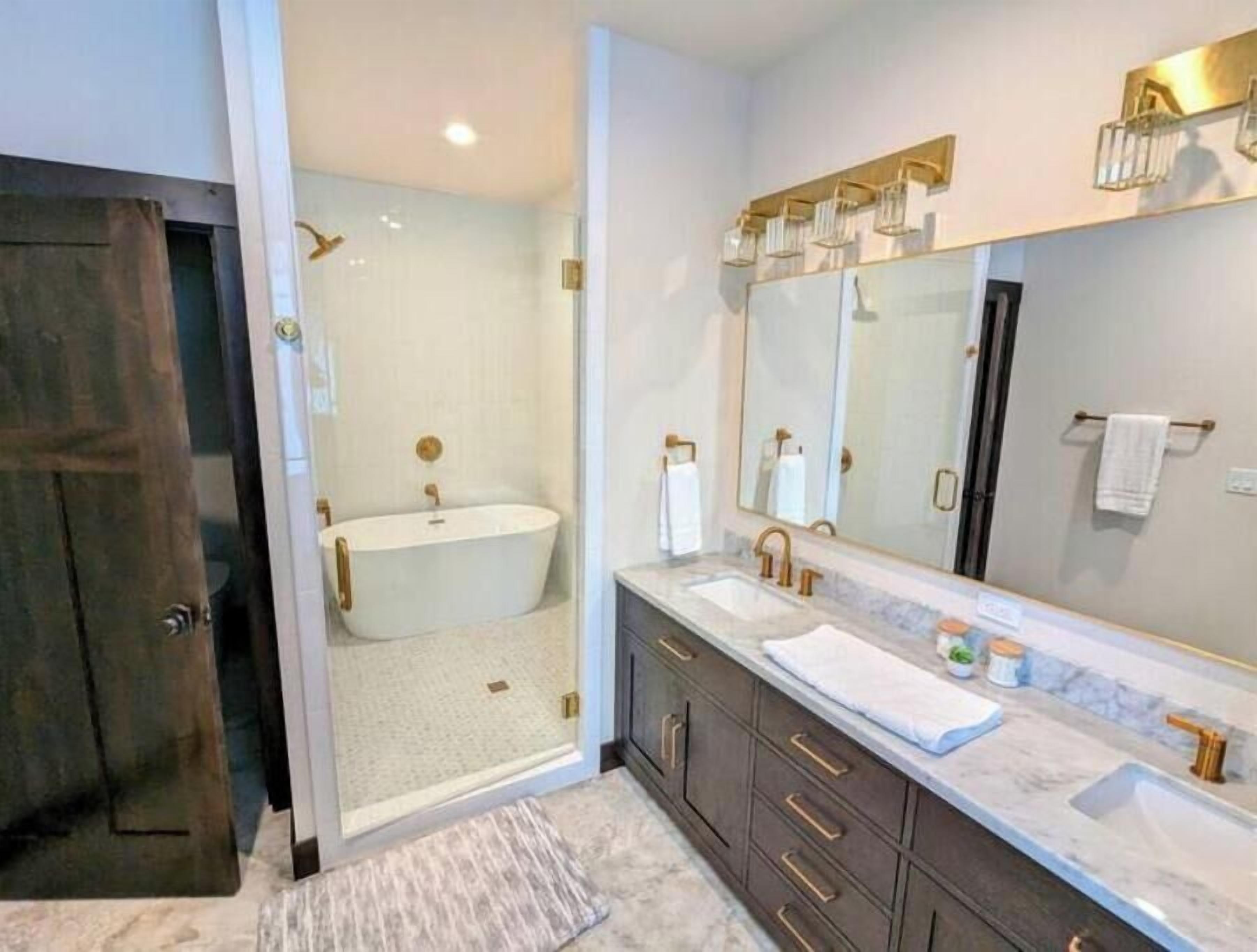 A modern bathroom with a freestanding bathtub, a large mirror, and dark wooden cabinets.