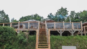 A wooden staircase leading to a glass bridge over a forested area with a bench nearby. - Copper Lodge (Chulmleigh)