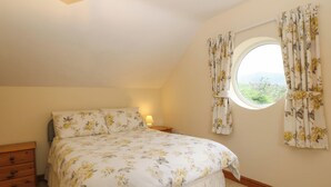 Une chambre à coucher avec un lit, une table de chevet, une commode et une fenêtre avec des rideaux.