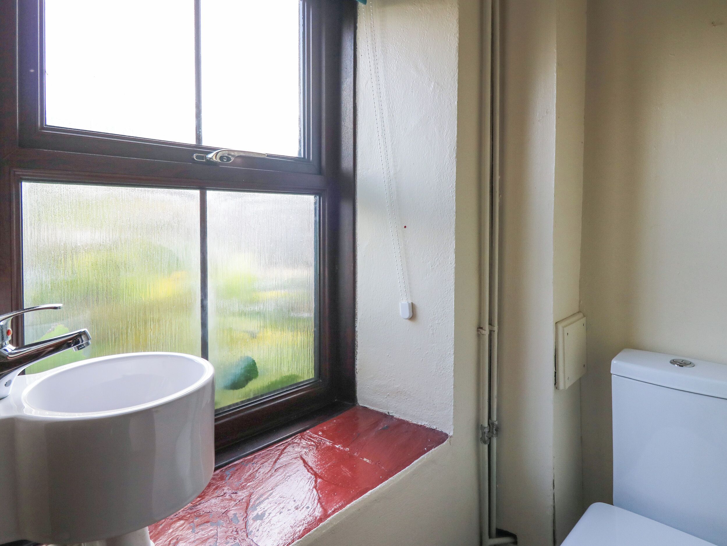 A bathroom with a window, a sink, and a toilet.