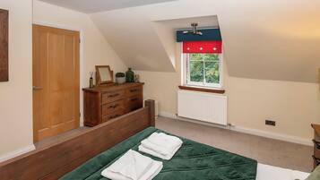 A bedroom with a bed, a dresser, a window, and a radiator.