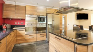 Une cuisine moderne dotée d’appareils électroménagers en acier inoxydable, de meubles en bois et d’un plan de travail noir.