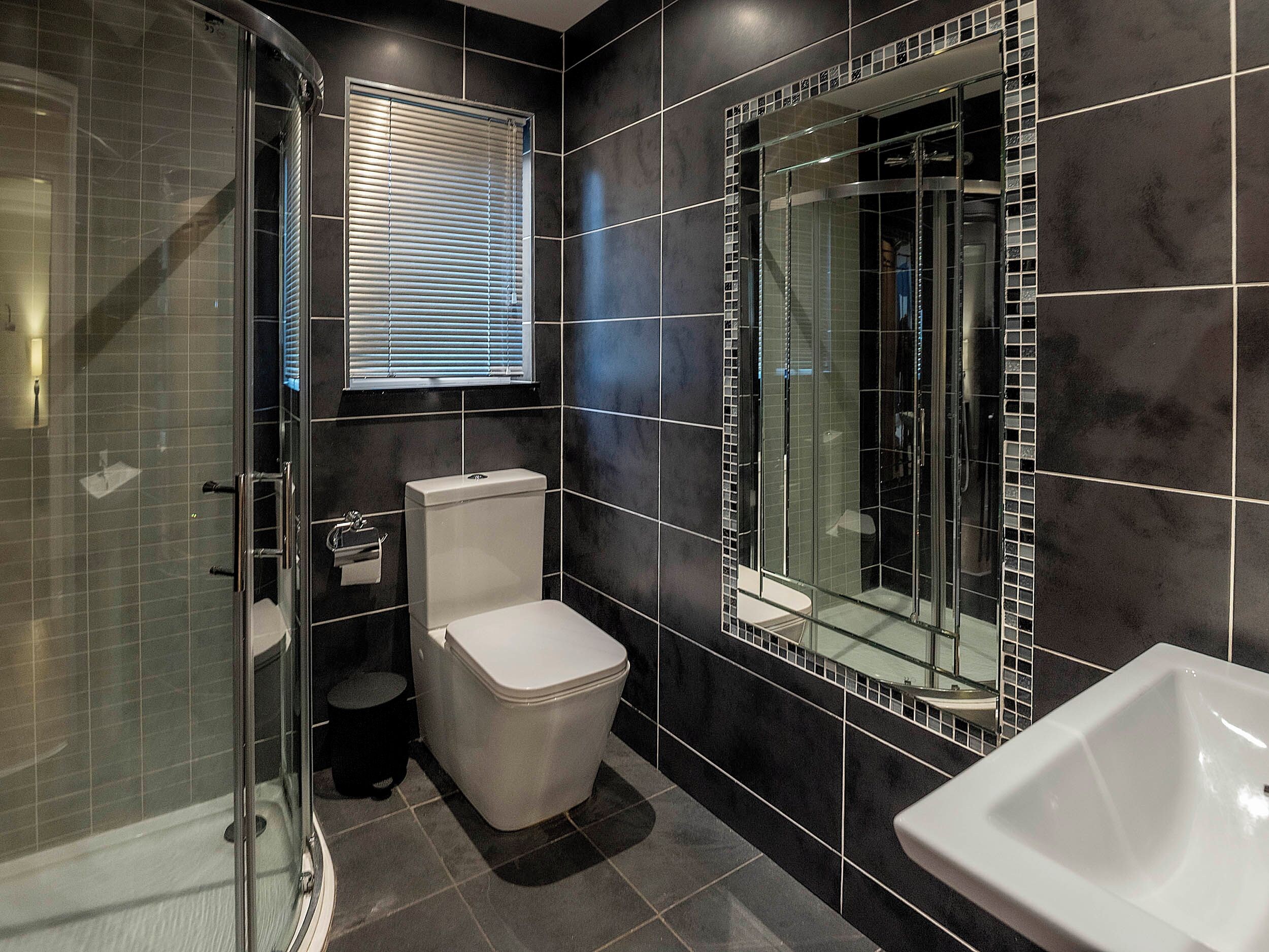 A modern bathroom with a glass shower enclosure, a toilet, and a sink.