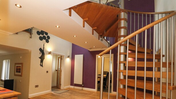 Une pièce spacieuse avec un escalier en bois et un plafond doté d’un éclairage encastré.