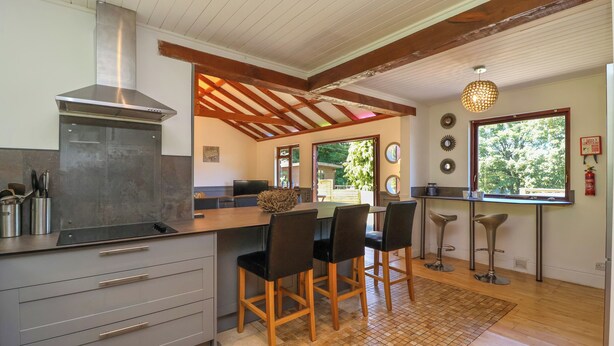 A modern kitchen with a large island, bar stools, and a view of the outdoors. - Bay Tree Lodge 35 (Ilfracombe)
