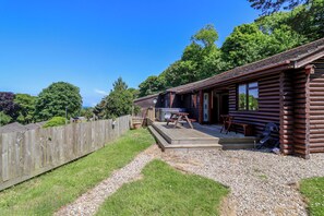 A rustic log cabin with a deck, outdoor seating, and a gravel path. - Bay Tree Lodge 35 (Ilfracombe)