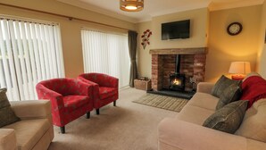A living room with two sofas, a fireplace, and a television mounted on the wall. - The Stables at Daldorch (Mauchline)