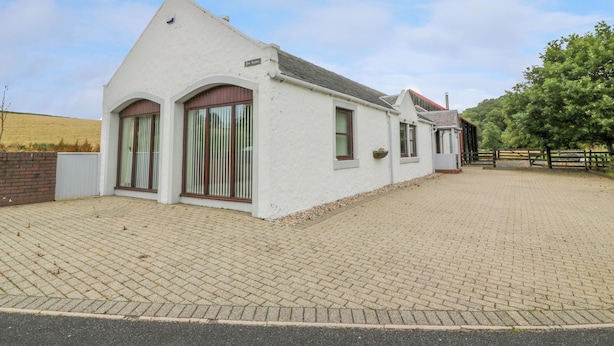A white building with a pitched roof, large windows, and a brick pathway leading to it. - The Stables at Daldorch (Mauchline)