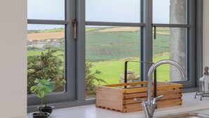 A kitchen with a large window, a wooden crate, and a potted plant. - Nancherrow Studio (Penzance)