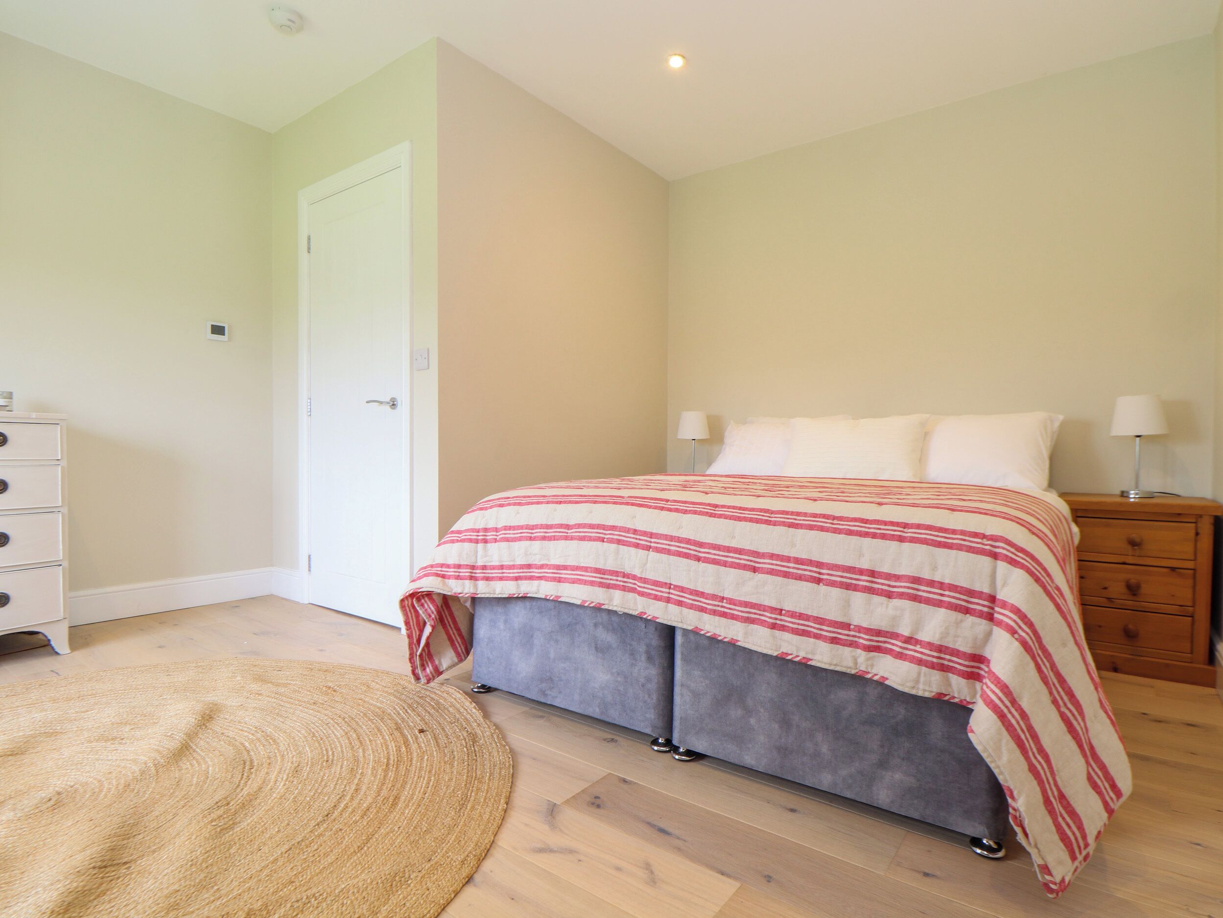 A bedroom with a bed, bedside tables, a dresser, and a rug.